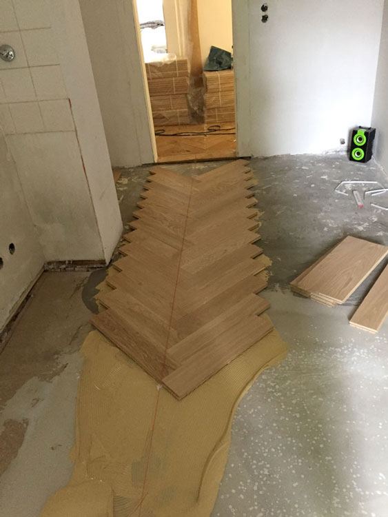 Fischgrätparkett wird in einem schmalen Flur verlegt
