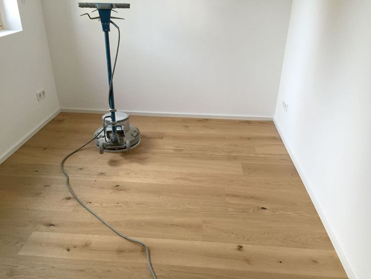 Schleifmaschine auf hellem Parkett in einem leeren Raum