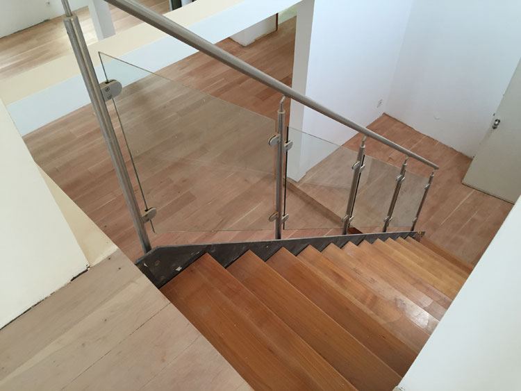 Blick von oben auf eine versiegelte Holztreppe mit Glasgeländer