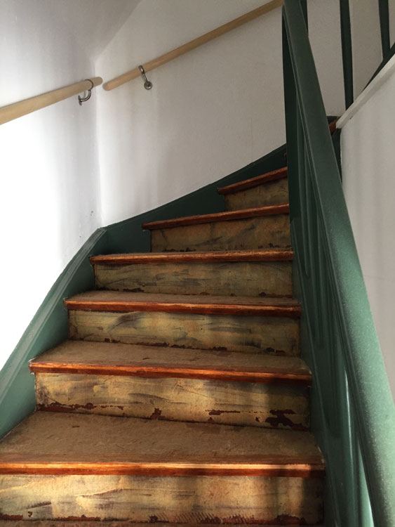 Gewendelte Holztreppe mit abgenutzten Stufen vor der Sanierung
