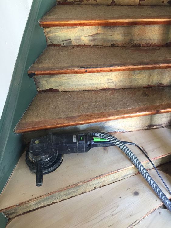 Schleifgerät mit Absaugung auf einer abgenutzten Holzstufe