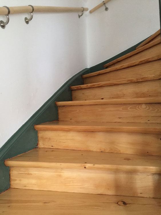 Gewendelte Holztreppe mit Handlauf nach der Sanierung