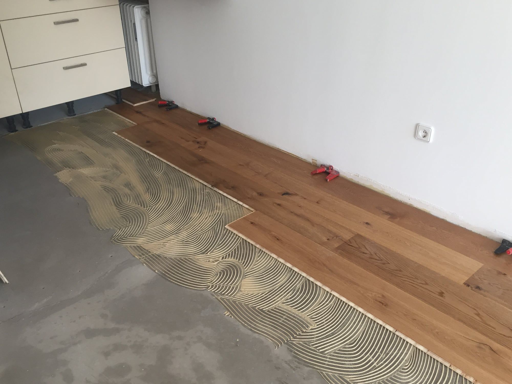 Landhausdielen werden in das gezahnte Kleberbett auf dem Estrich gelegt