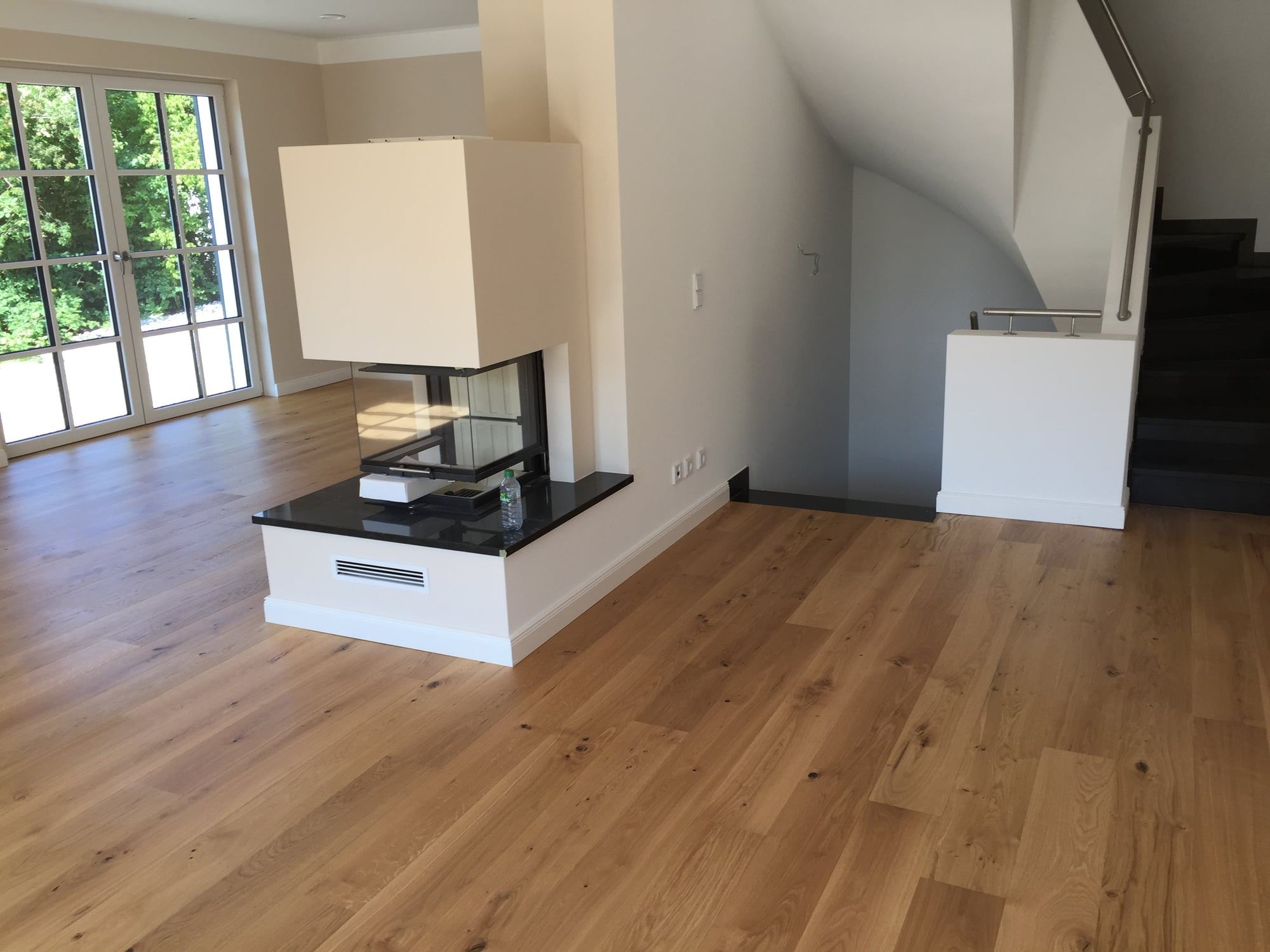 Wohnraum mit Eichen-Landhausdielen, freistehendem Kamin und Treppe