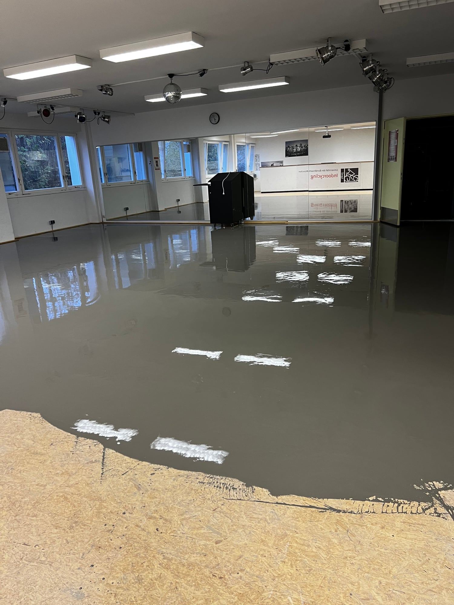 Frisch aufgebrachte Ausgleichsmasse in einem großen Raum, vorn noch die alte Holzplatte